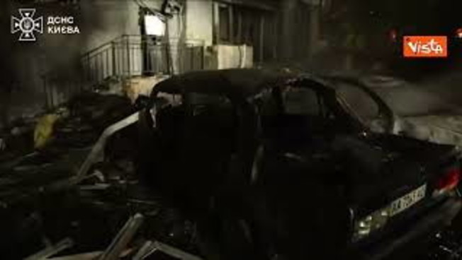 Auto in fiamme accanto a un edificio durante un attacco notturno, immagine di approfo