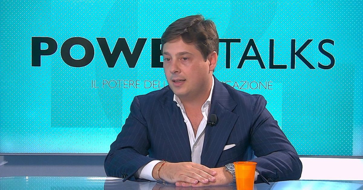 Intervista su transizione energetica e comunicazione, palazzo moderno con professionisti, simboli energia rinnovabile sullo sfondo, immagine di approf