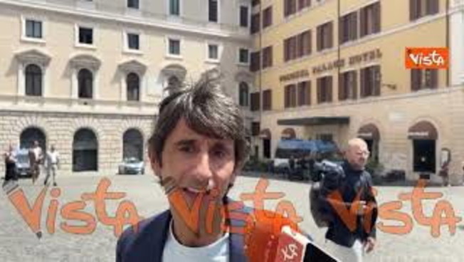 Giovanni Donzelli parla ai microfoni in piazza Montecitorio davanti a Palazzo del Parlamento, immagine di approfondimento